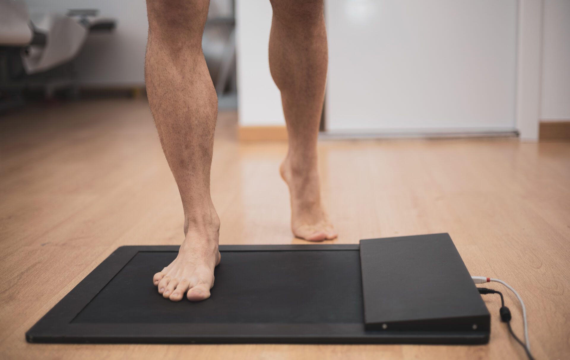 Feet and legs of man standing on MatScan device for an assessment.