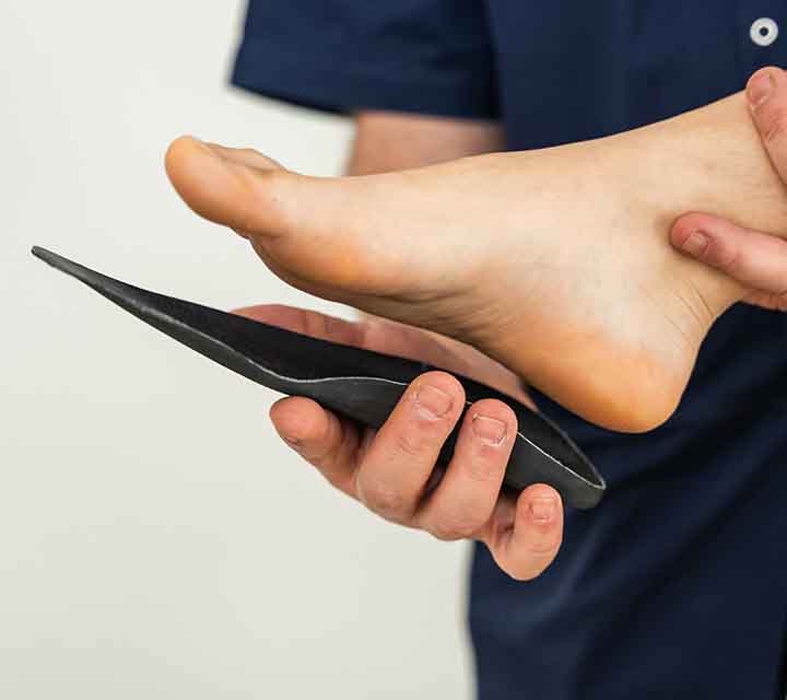 Custom Orthotic Insole being fitted against bottom of bare foot.