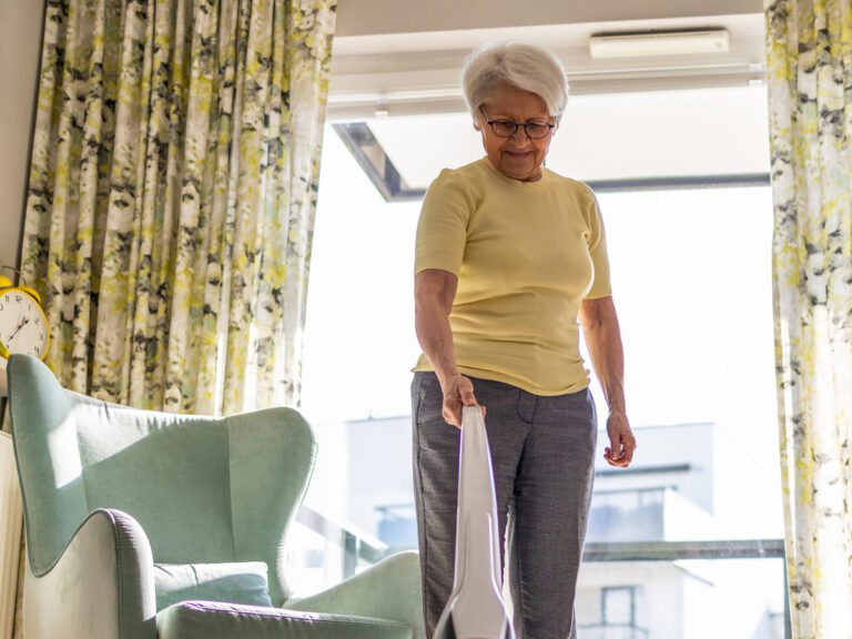 Senior woman getting exercise by vacuuming her living room