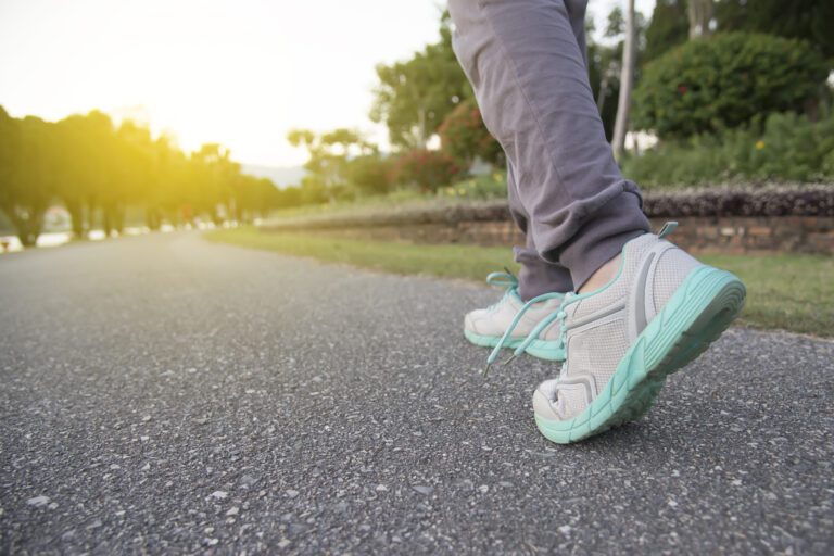 Lower legs of a person going for a walk on a sunny day, wearing proper athletic shoes.