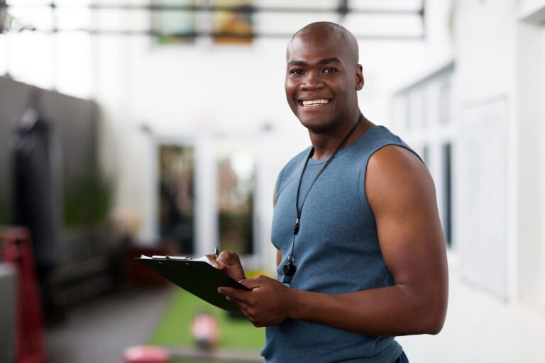 A smiling, friendly african american health coach holding a clipboard, ready to help.